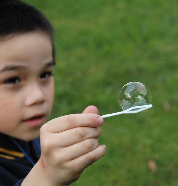 Michael holds a bubble on a bubble blower