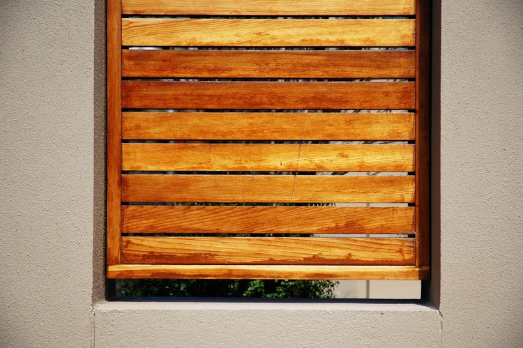 Wooden slats cover a gap in a concrete fence