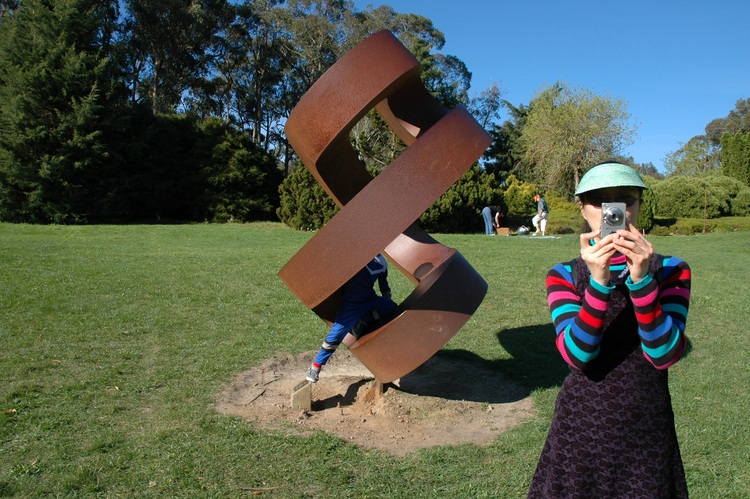 Theen takes a photo in front of a steel sculpture