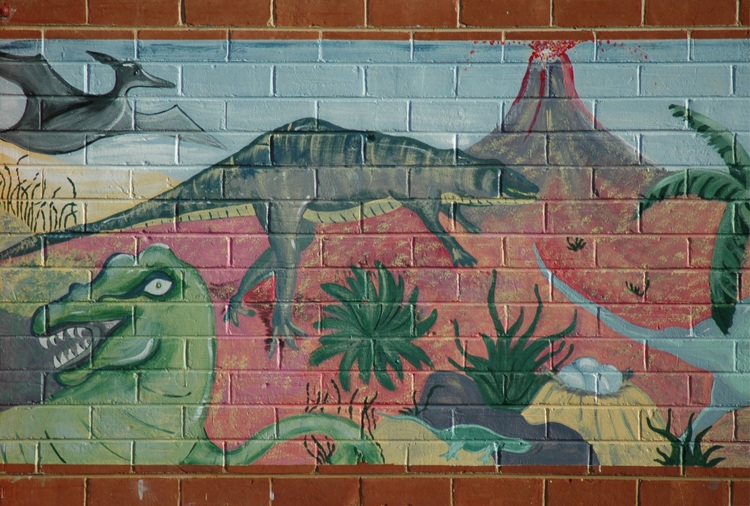 A dinosaur mural on a brick wall