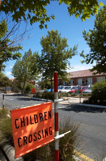 Streetscape with an orange school crossing sign in the foreground