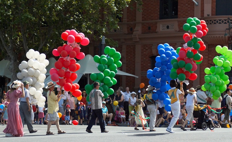 People carrying large single-colour bunches of balloons