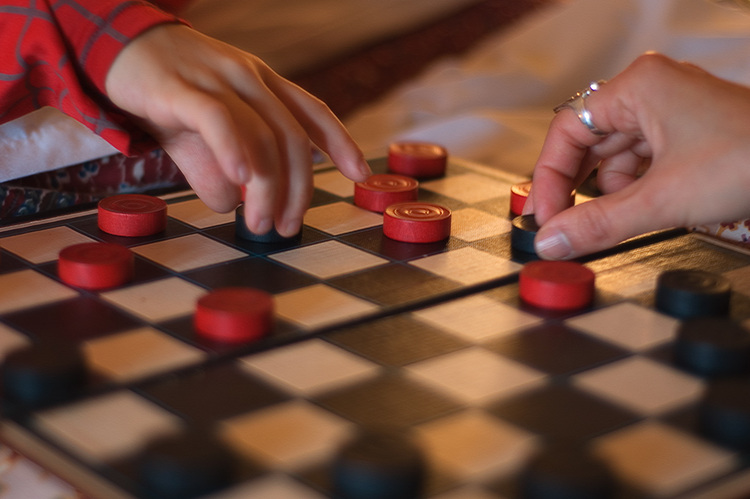 Hands moving pieces on a draughts board