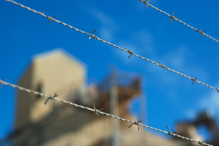 Barbed wire against a blue sky and buildings