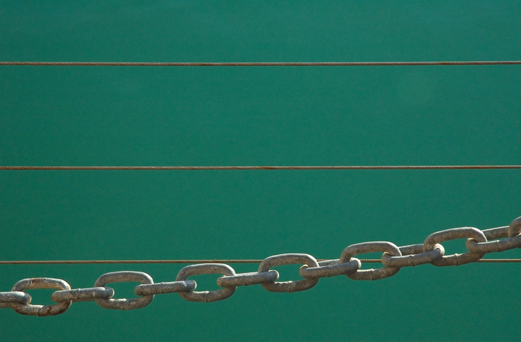 Fence chain links and wires, against an water background