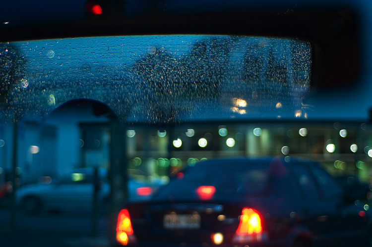 Drops of rain on the rear windscreen, and blurred car lights