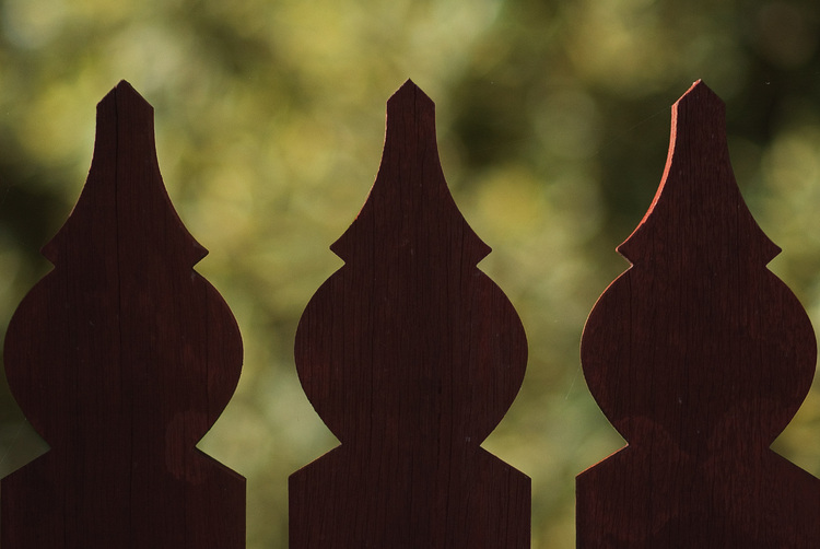 Three fence pickets silhouetted against foliage