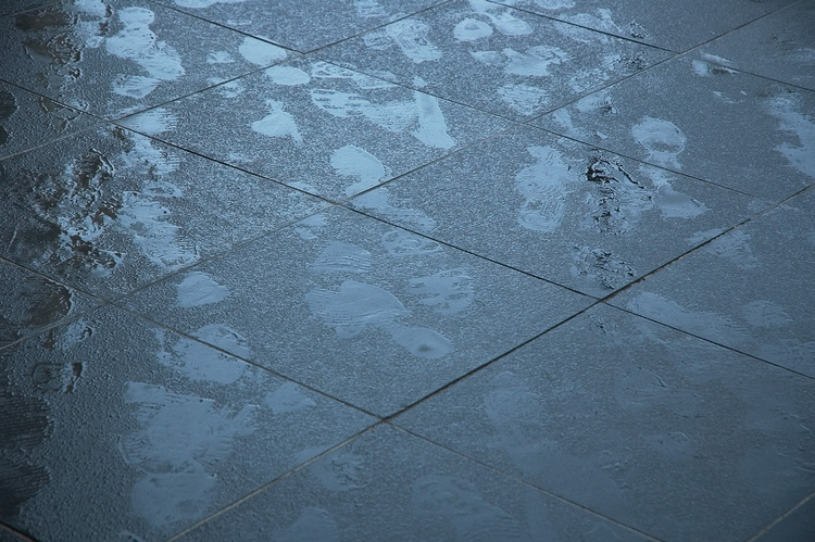 Footprints on lightly drizzled-on pavement