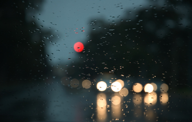 Headlights behind drops of rain on a windscreen