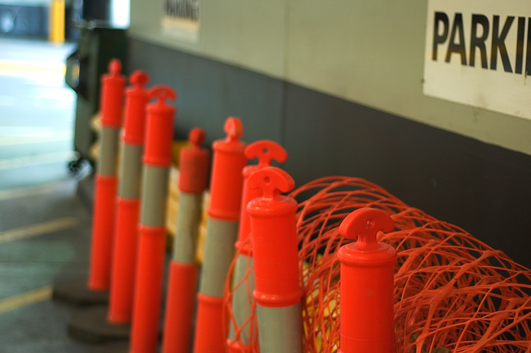 Orange safety cones, lined up next to a wall