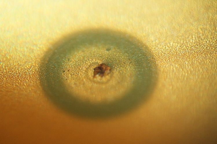 Closeup of a CD with a hole burnt into the metalized layer