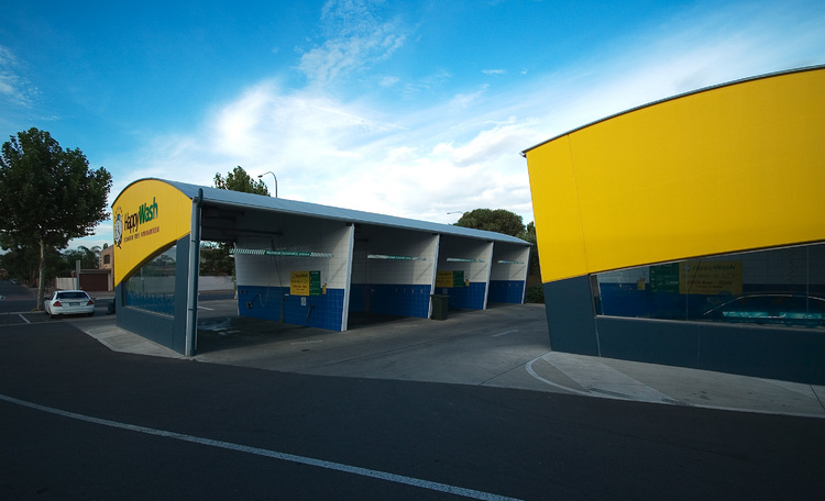 A bright yellow car-wash, against a blue sky