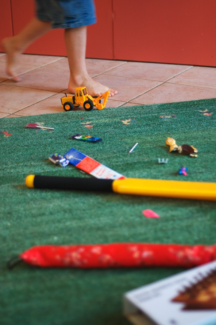 A child walking past toys that are scattered on the floor