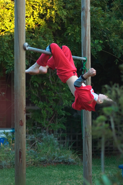 Michael swinging, upside down, on a bar