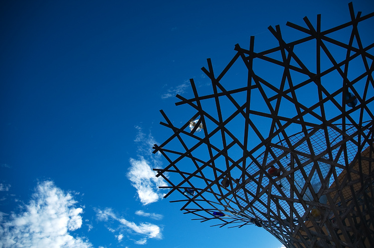 Looking up at a fountain/sculpture with a deep blue sky beyond