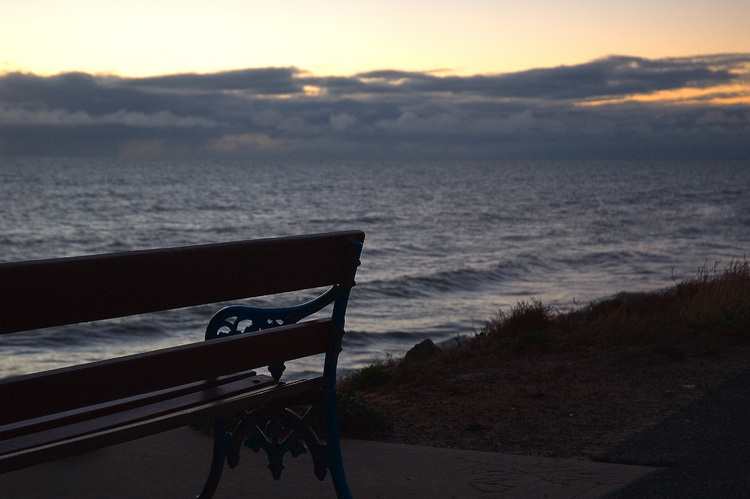 An empty bench, looking out over the sea at dusk