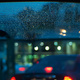 Drops of rain on the rear windscreen, and blurred car lights