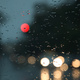 Headlights behind drops of rain on a windscreen