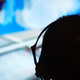 The silhouette of a head (wearing headphones), against a a TV screen