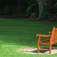 An empty park bench in the middle of a lawn