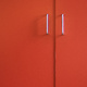 A pair of cupboard door handles on orange doors